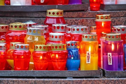 Lot of illuminated votive candles glows on a grave