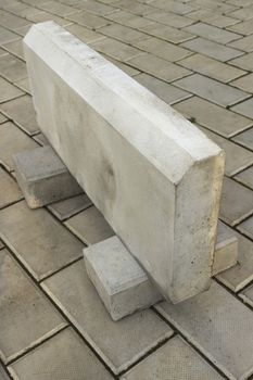 Large curb stone is made of concrete, on the stone floor