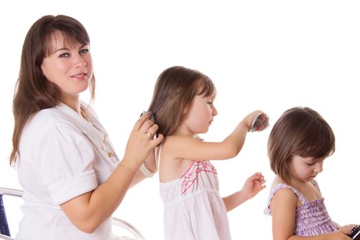 Mother and two daughters combing hair to each othre isolated on white