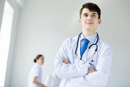 Young doctor in uniform and colleagues at background