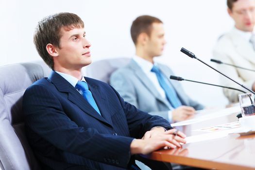 Image of three businesspeople at table at conference