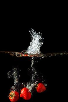 Colored red paprika in water splashes on black background