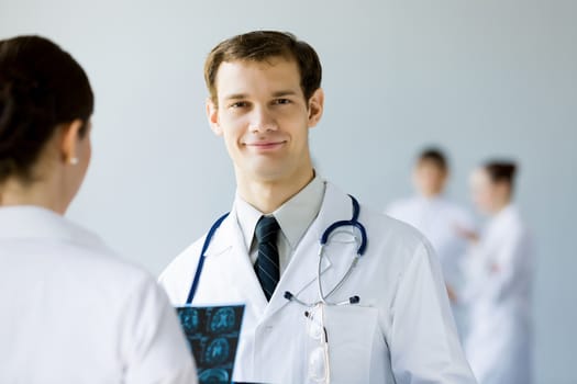 Young doctor in white uniform talking to colleague