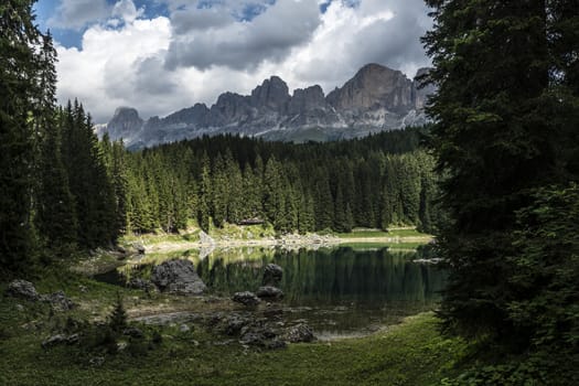 Carezza lake and Catinaccio in summer season with clouds, Dolomites - Italy