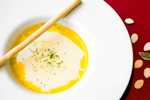 A bowl of pumpkin soup, swirled with coconut cream and bread stick