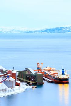 Industrial Container Cargo freight ship with working crane bridge in shipyard at Iron Ore Mine Factory Plant in Narvik Norway