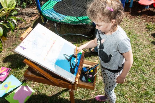 Having fun painting at easel in a garden on sunny day.