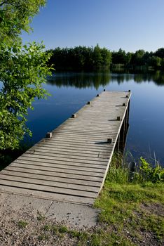  wooden pier on a quiet blue pond in Denmark