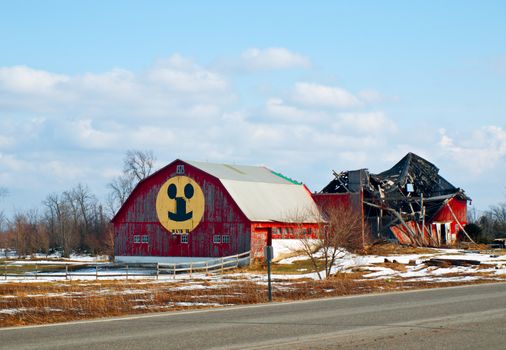 barn with smiley face next to collasped barn structure