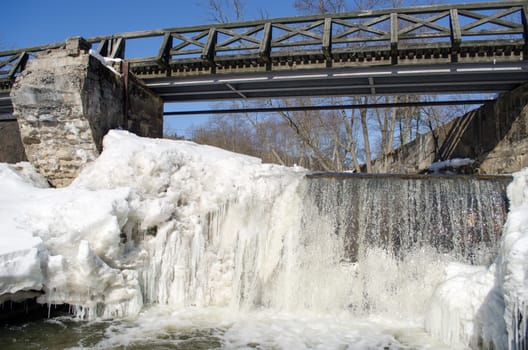 wonderful river cataract waterfall covered with frozen ice and reflections on flow water.