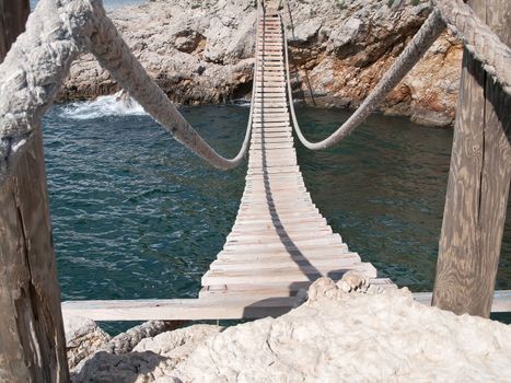 hanging wooden bridge connect rocky seacost