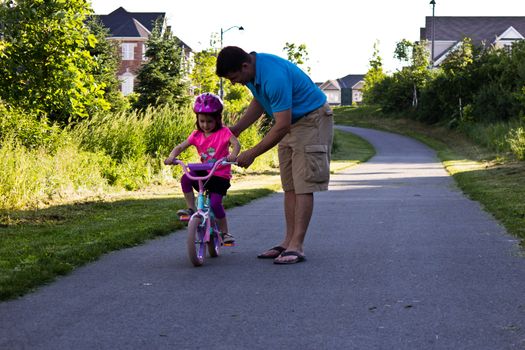 Child learning to ride a bicycle with father