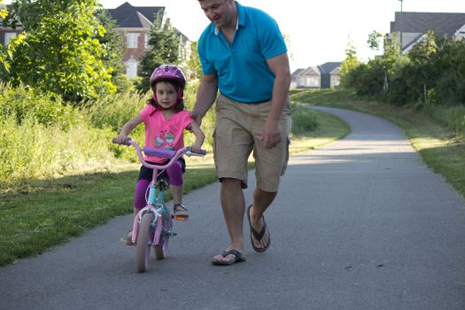 Child learning to ride a bicycle with father