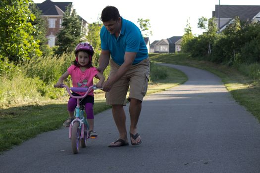 Child learning to ride a bicycle with father