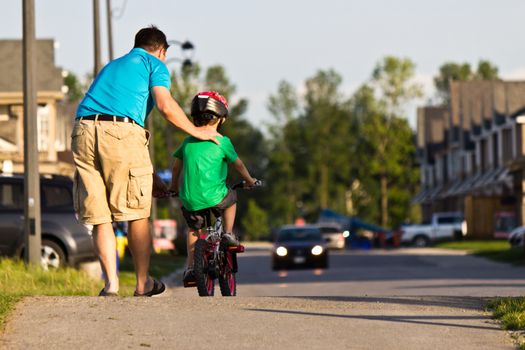 Child learning to ride a bicycle with father