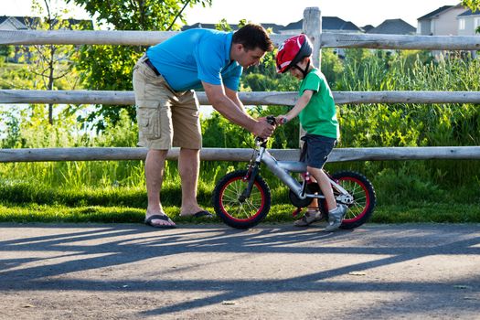 Child learning to ride a bicycle with father