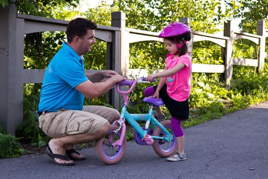 Child learning to ride a bicycle with father