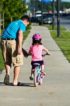 Child learning to ride a bicycle with father