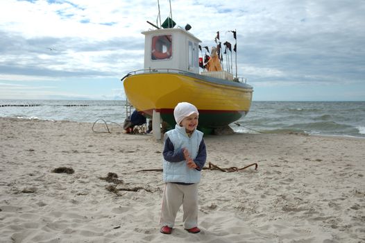 Little girl and fishing boat on beach somewhere in Poland