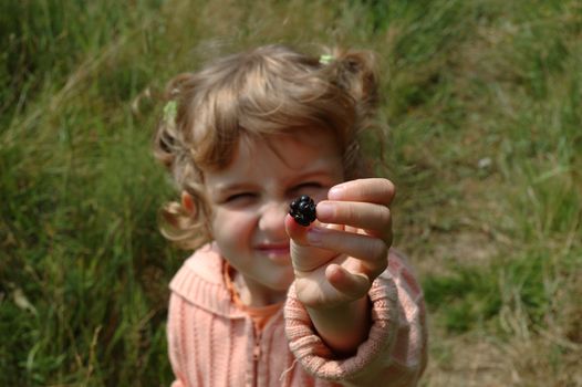 Little girl holding blackberry in her hand