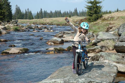 Little girl with bicycle on river bank in izerskie mountains in Poland