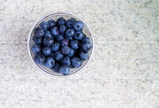 Blueberries in a plastic cup shot from above on a concrete surface