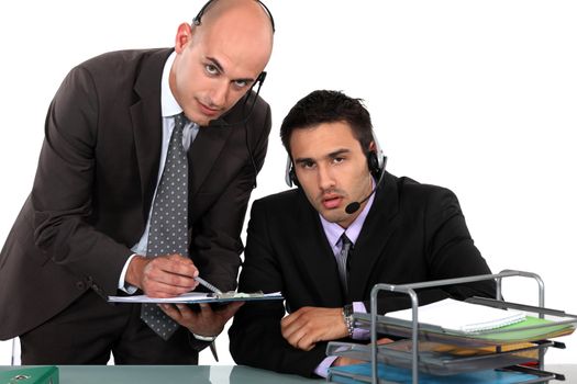 two businessmen at the office wearing headsets