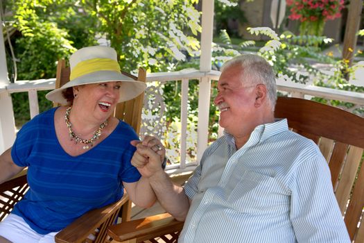 Happy couple senior looking at each other in the gazebo happily and woman have her hat on.