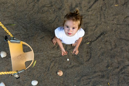 A little girl beside a swing in a beach.
