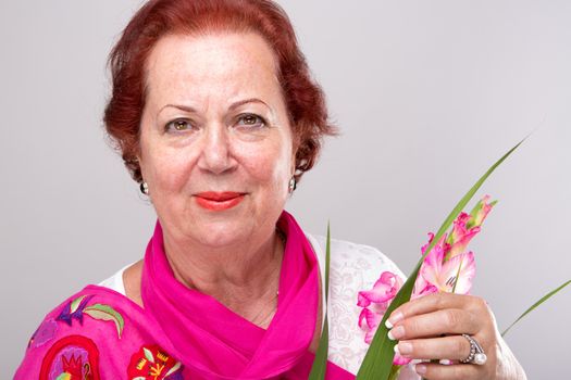 Red Hair Senior Woman with Gladiolus flower looking determined.