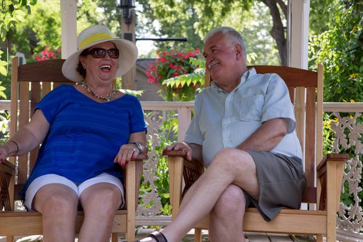 Retired couple having fun conversations. Woman is laughing while her husband happily looking at her