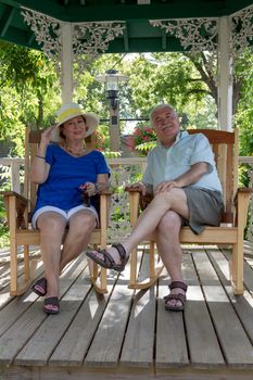 Senior couple resting in the gazebo protecting themselves from the sun