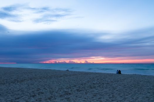 Romantic couple watching the waves and sunrise at the beach. Cozumel Mexico