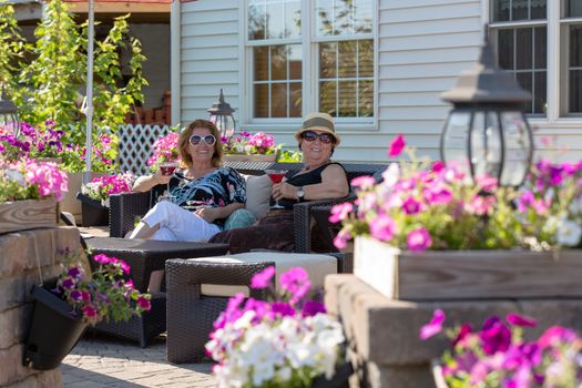 Senior ladies having their martinis with cherries in a flower full brick patio.