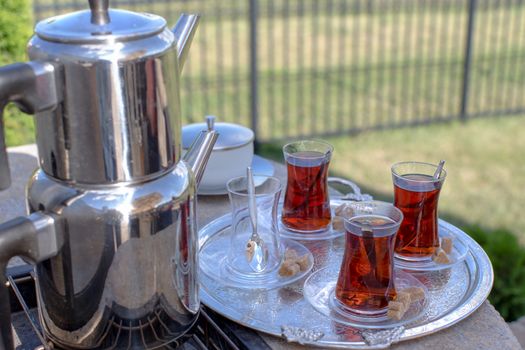 Traditional strong black Turkish tea served with contemporary kettle and glasses along with brown sugar