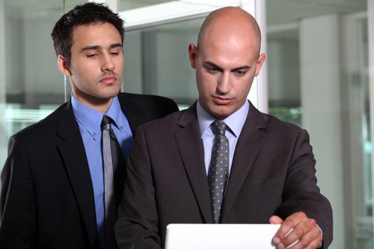 Two young businessmen stood with portable computer