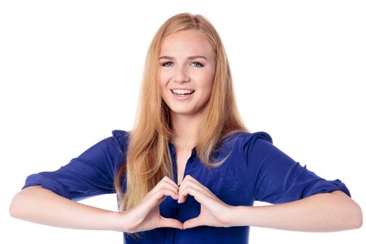 Romantic sentimental young woman with a beautiful smile making a heart gesture with her fingers to signal her feelings of love