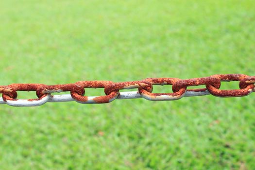 Old rusty metal chain links and green grass