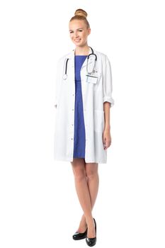 Relaxed elegant stylish female doctor standing in her lab coat and stethoscope with crossed legs smiling to the left of the frame, isolated on white
