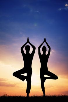 Couple doing yoga at sunset