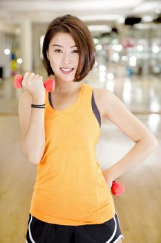 An Asian lady doing weight lifting exercise in a gym.
