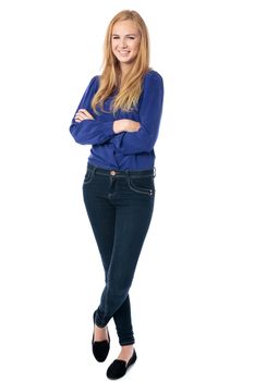 Happy confident relaxed young woman standing with crossed arms and legs smiling at the camera, isolated on white