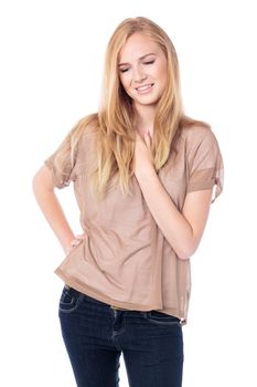 Pretty pensive young woman in a trendy summer top standing looking down with her hand to her chest lost in thought