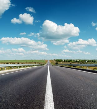 black asphalt road to horizon under deep blue cloudy sky