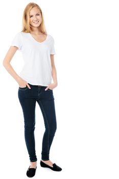 Slender friendly young woman in trendy jeans standing relaxing with her hands in her pockets smiling at the camera, isolated on white