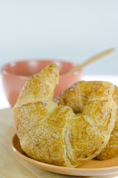 close up  croissants on  brown dish  and a brown cup of coffee with spoon , fresh food