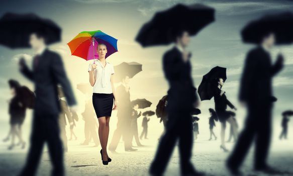 Image of pretty businesswoman with umbrella walking in crowd of people
