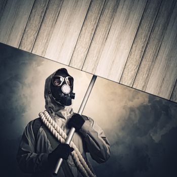 Stalker in gas mask with wooden banner. Disaster concept