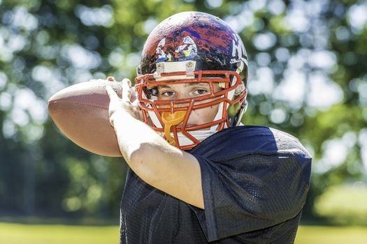 American Football Player with football and a heavily worn helmet