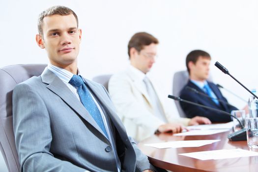 Image of three businesspeople at table at conference